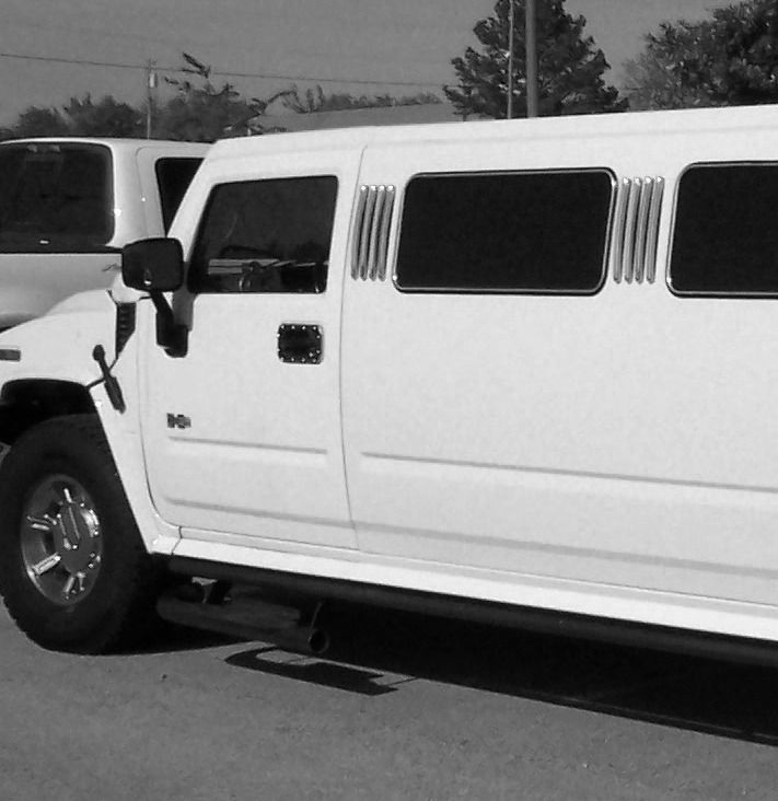 White stretch limousine parked in a lot, shown from the side in black and white.