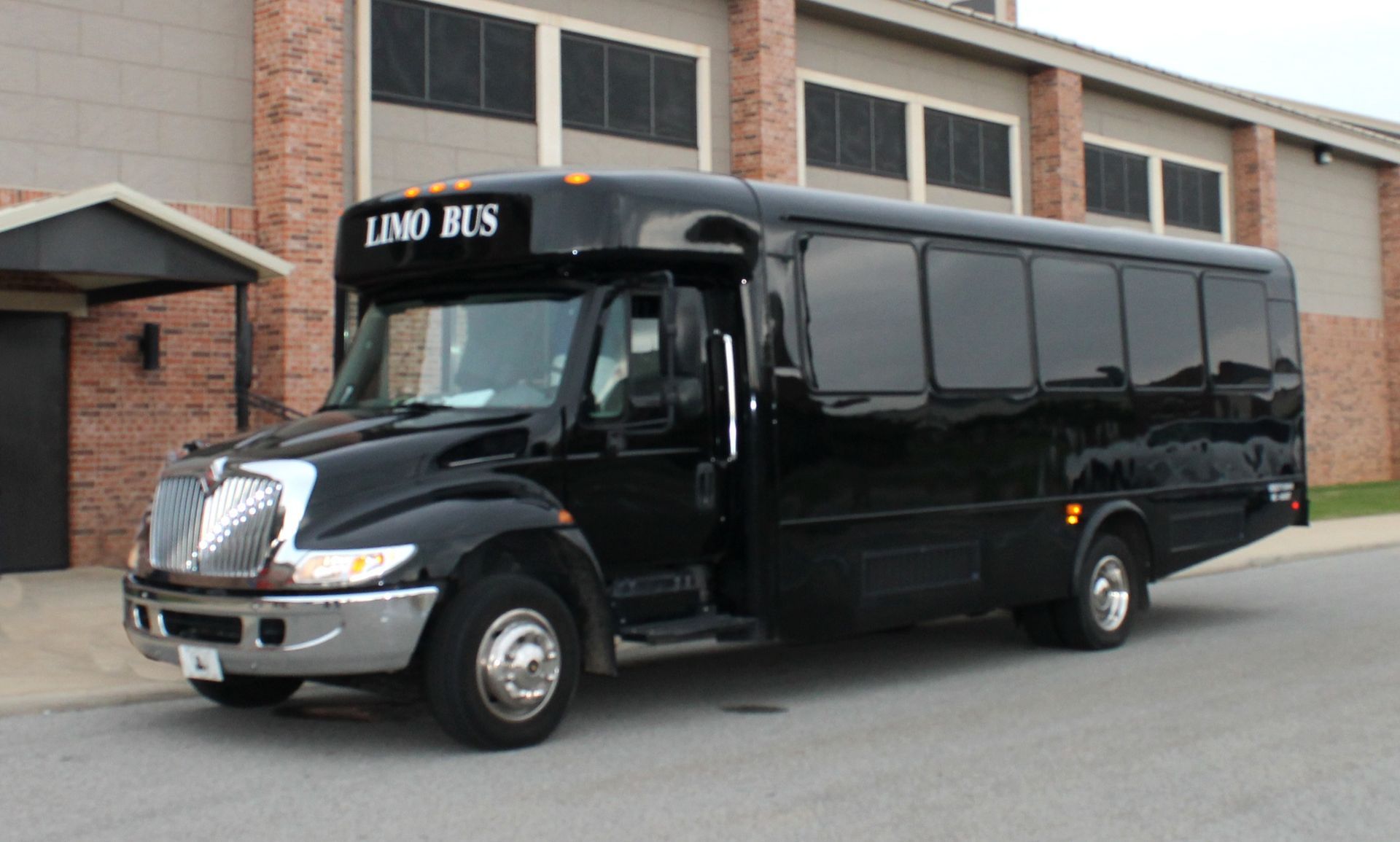 Black LIMD BUS shuttle parked outside a brick building