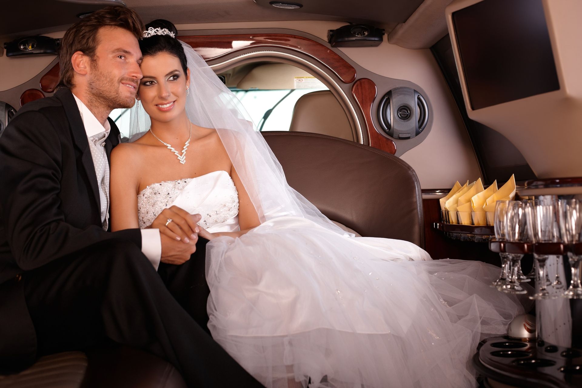 Bride and groom smiling in a luxury limousine with champagne on the table