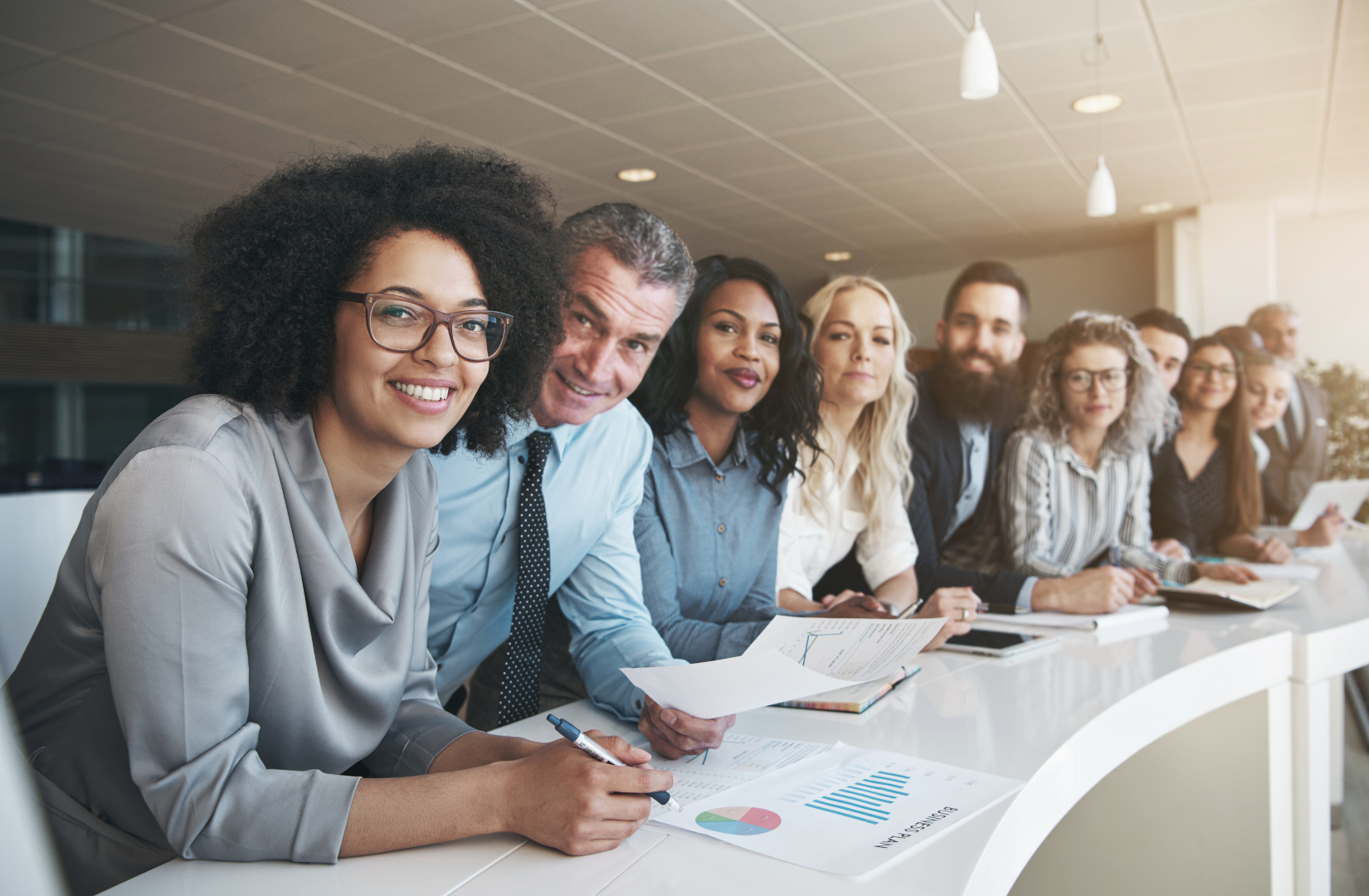 A diverse group of business people are sitting at a table in a conference room.