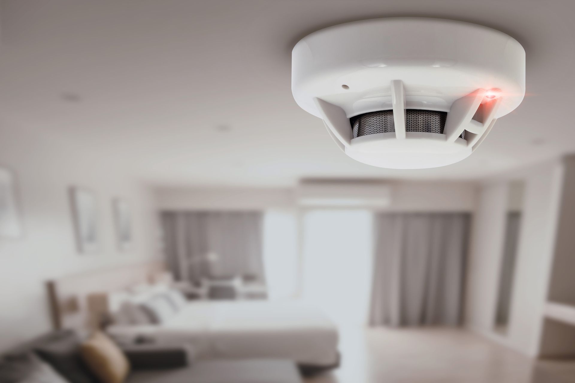 A white smoke detector fire alarm is installed on a room’s ceiling.