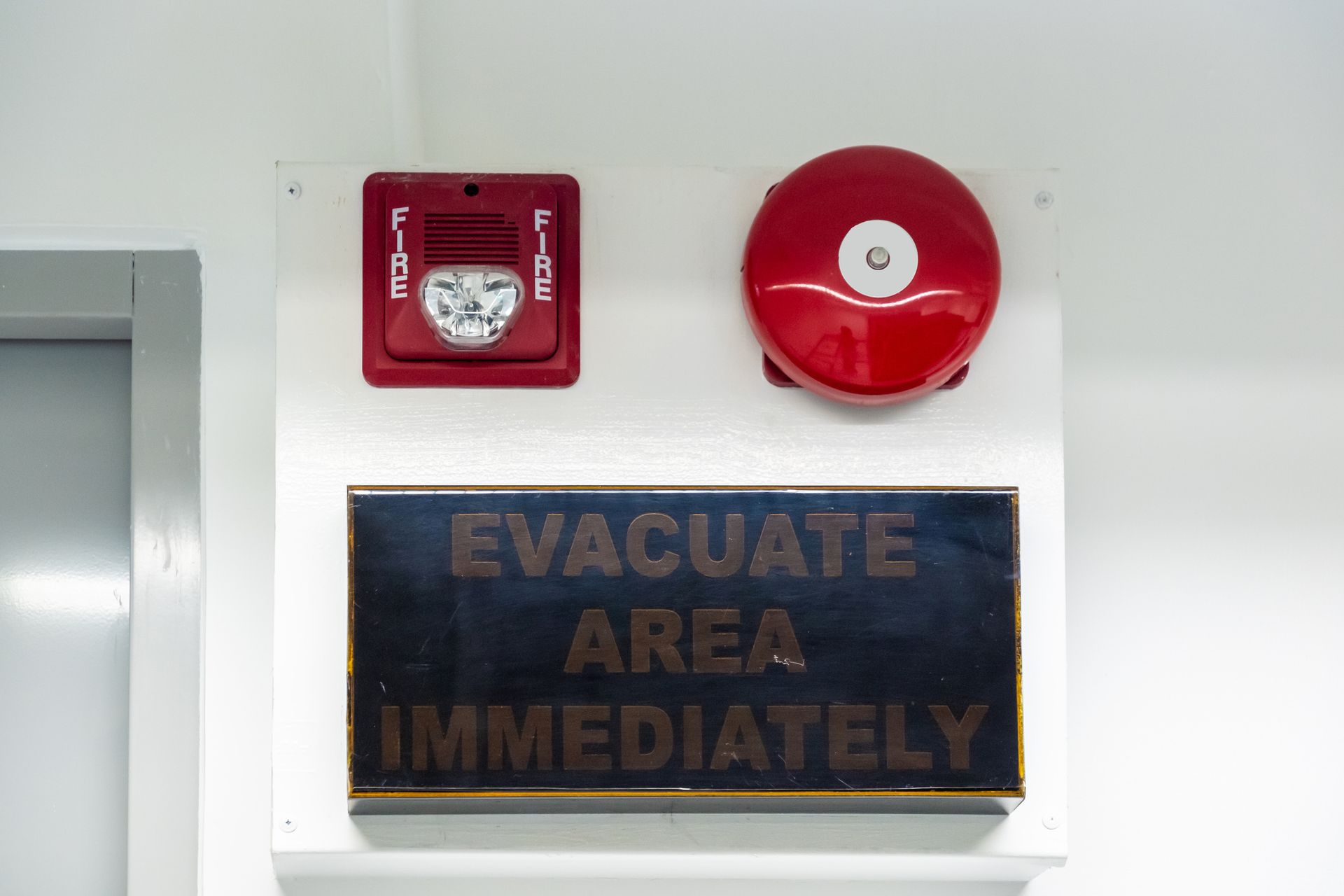 A fire alarm and evacuation sign on a white wall. A fire alarm and evacuation sign on a white wall.