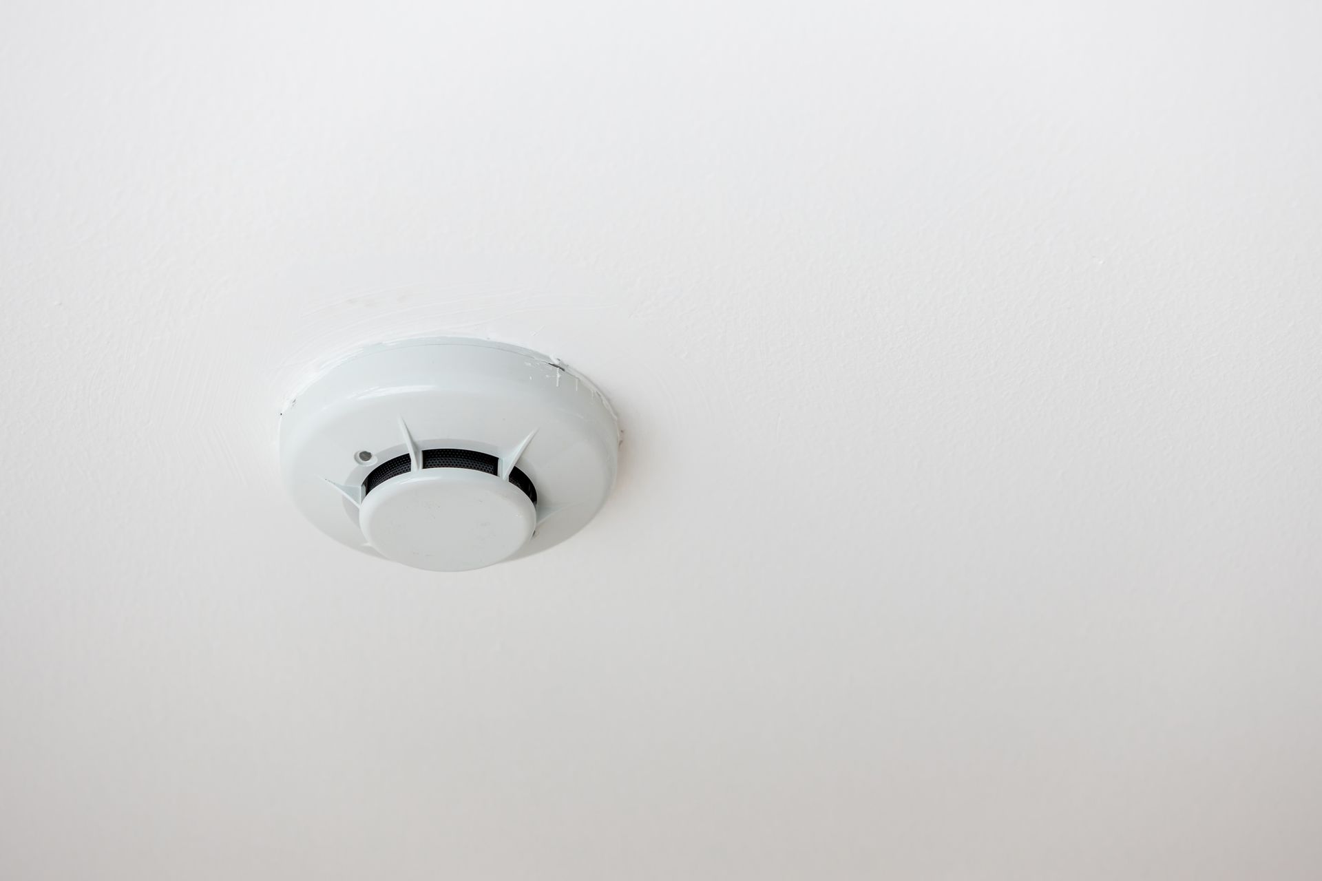 A white smoke detector mounted on a ceiling.