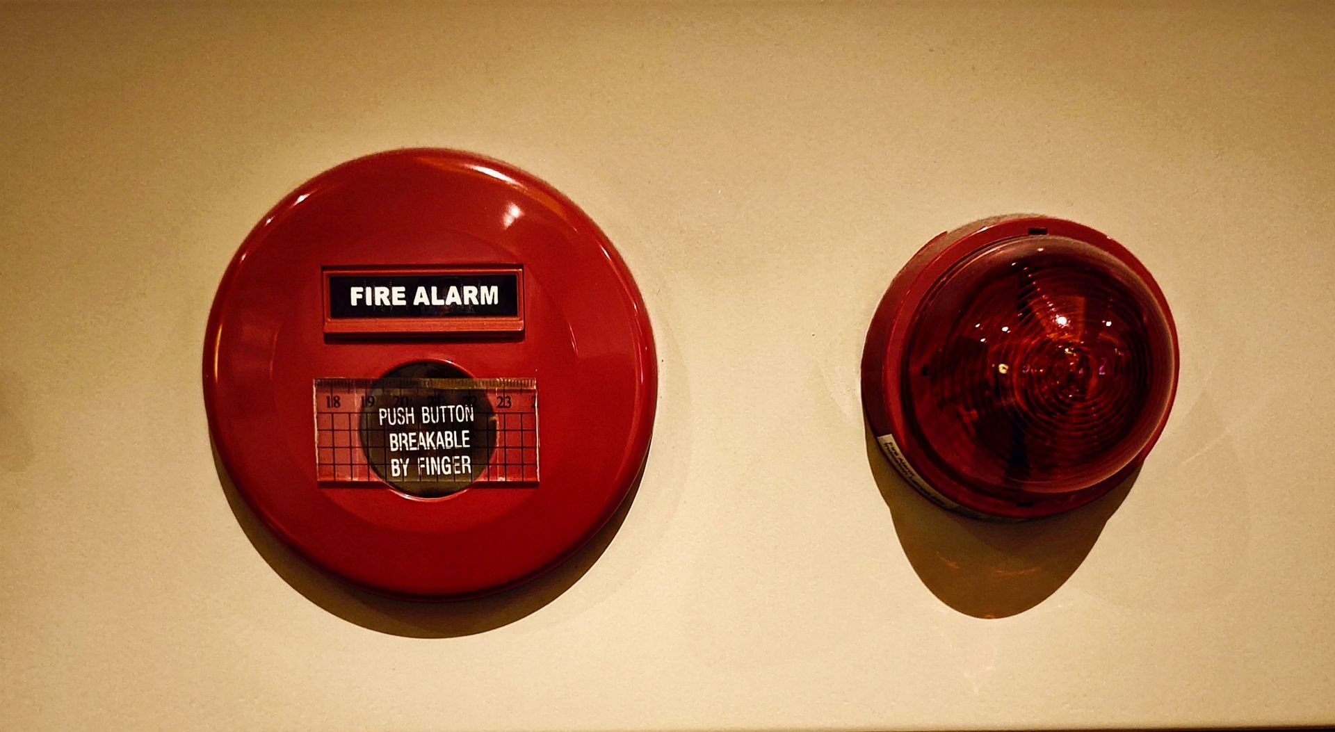 A red fire alarm and warning light mounted on a wall.