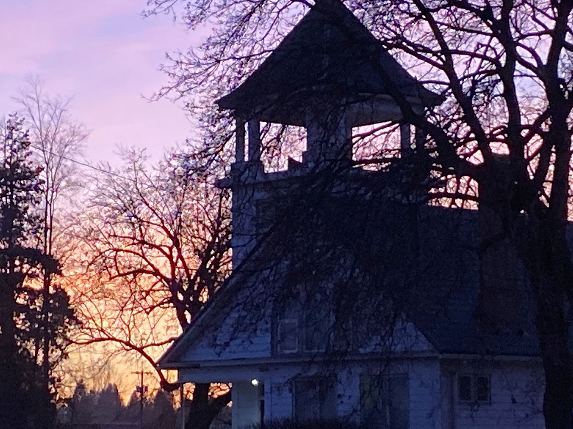 A family is sitting on the floor in their new home surrounded by cardboard boxes.