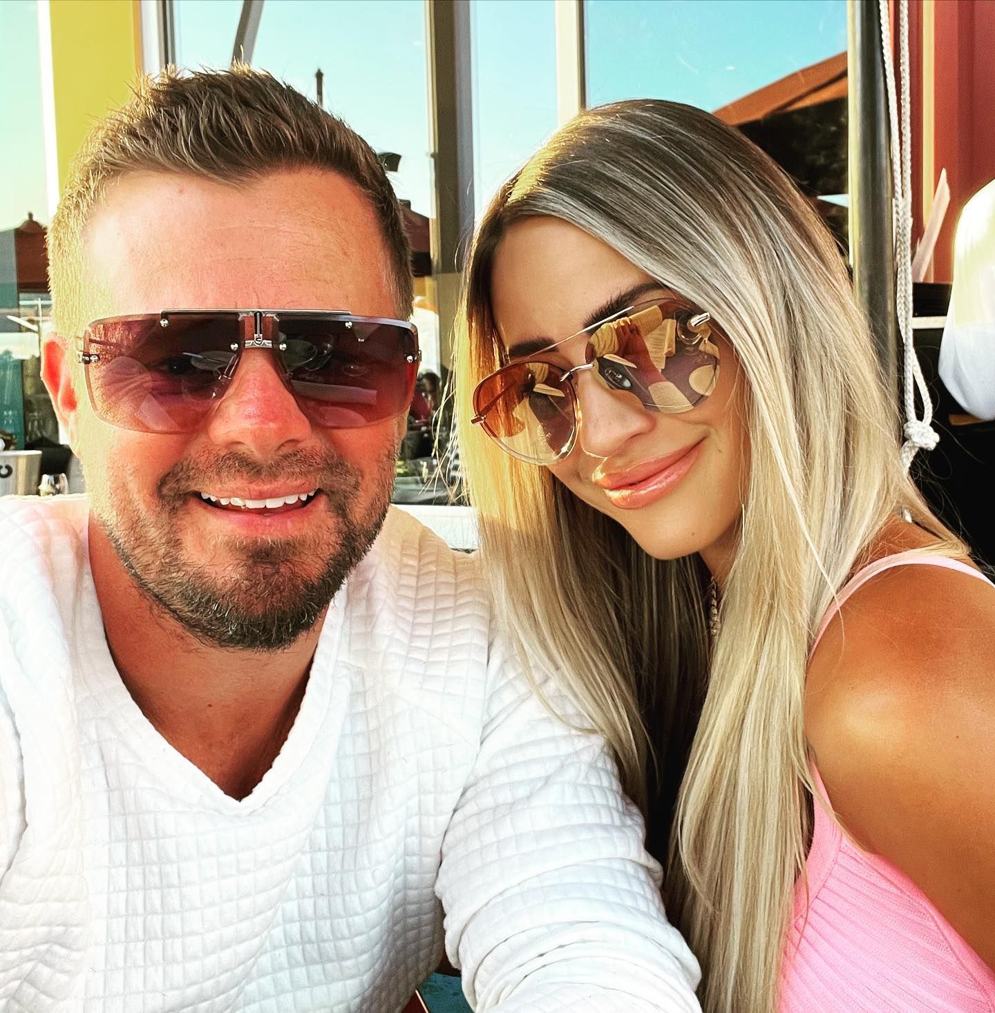 A man and a woman wearing sunglasses are posing for a picture