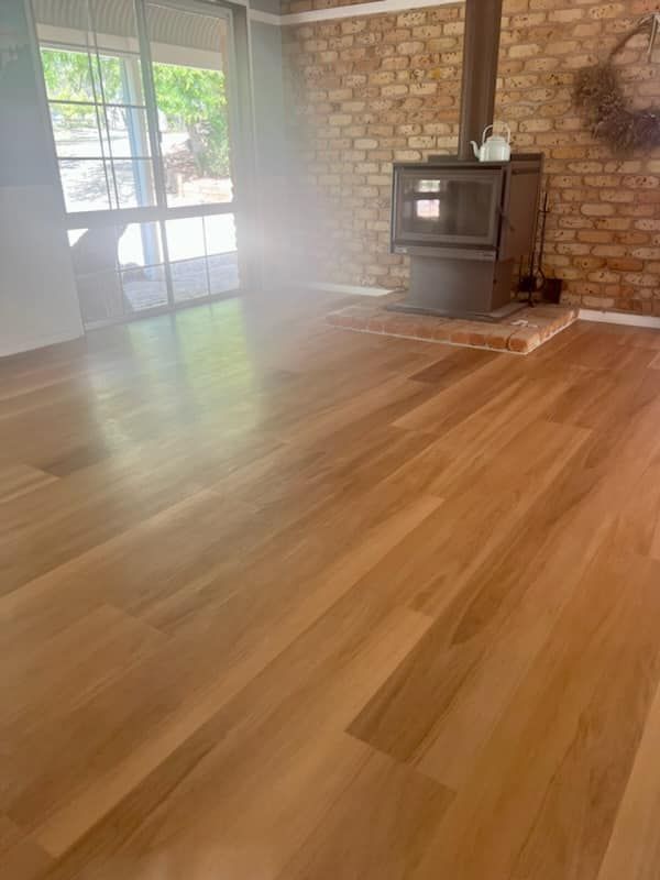 A Wooden Floor in a Room With a Fireplace — BLB Flooring Solutions in Raymond Terrace, NSW