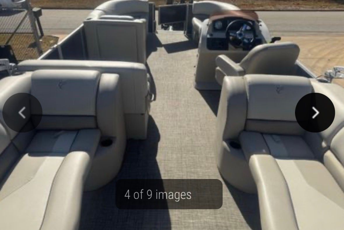 Interior view of a beige and white pontoon boat with seating and a steering wheel.