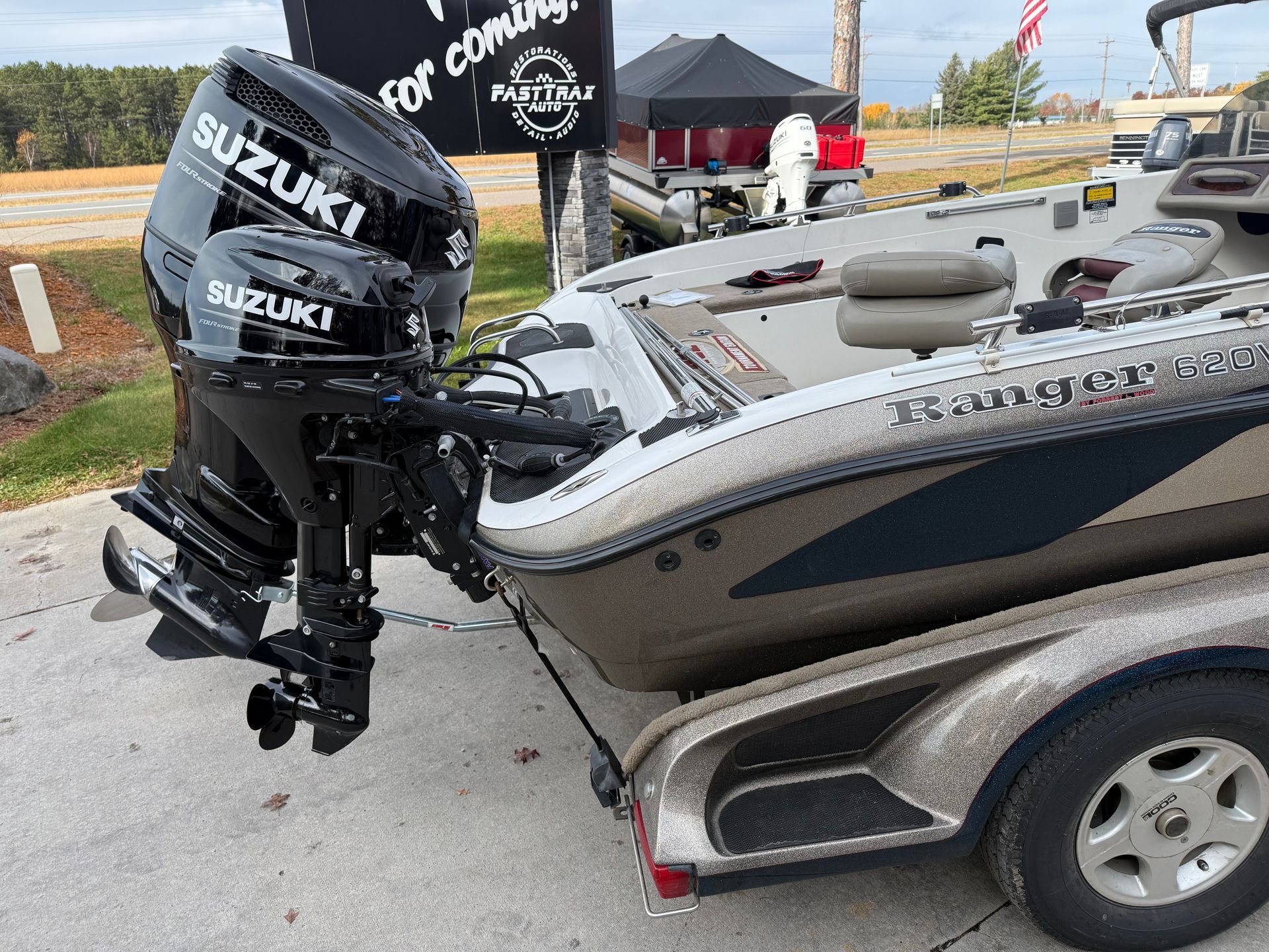 Suzuki outboard motor attached to a boat on a trailer, outdoors.
