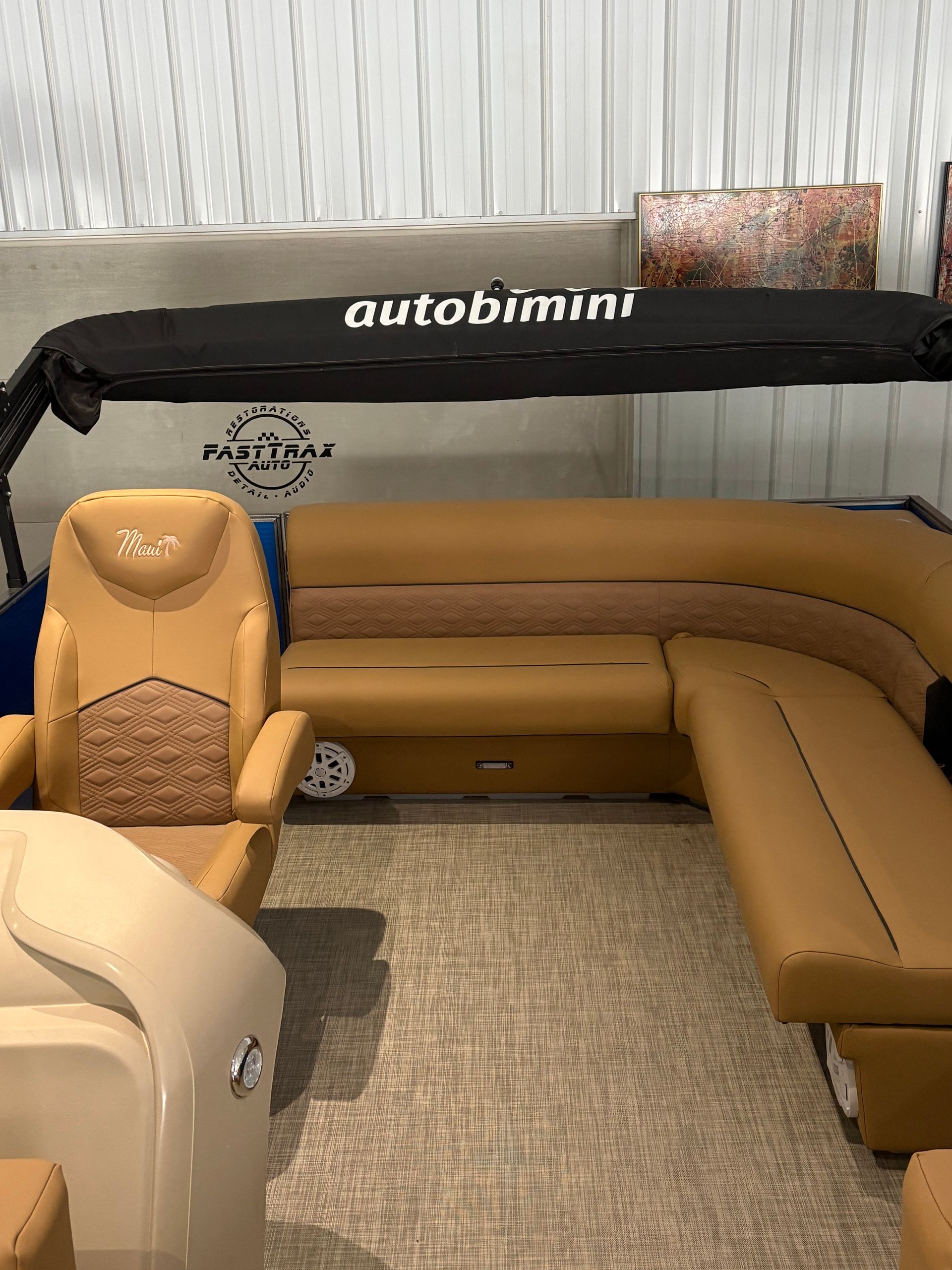 Interior of a boat with tan seating, a black canopy, and carpet flooring.