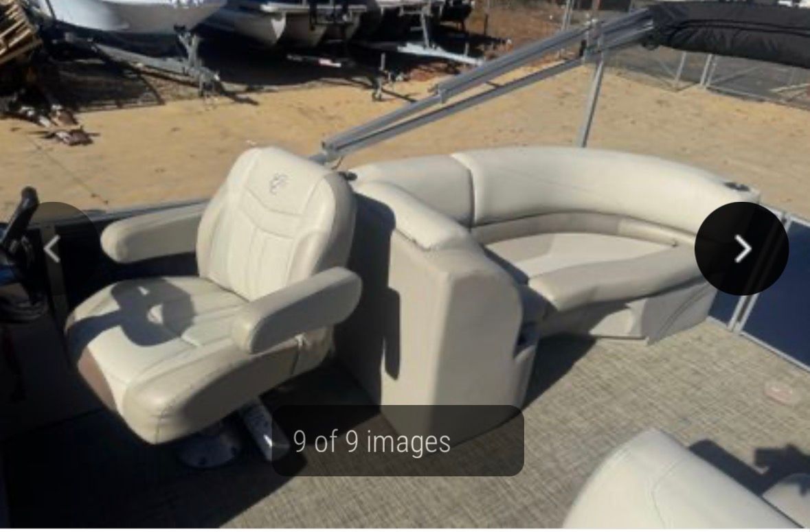 Pontoon boat interior with beige and gray seating, captain's chair, and a curved bench.