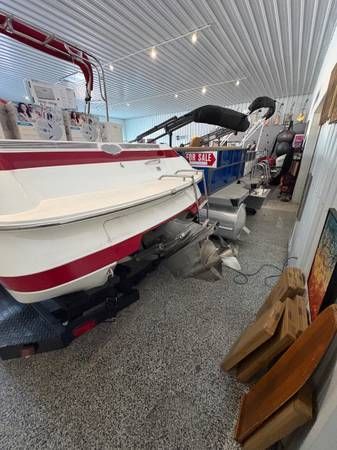 White and red boat on a trailer inside a building with a textured floor.