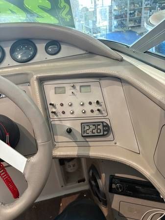Boat dashboard with steering wheel, gauges, switches, and digital clock showing 12:26.