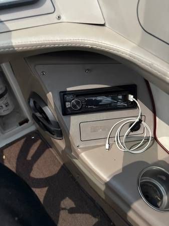 Boat dashboard with a stereo, speakers, USB cable, and cup holder.