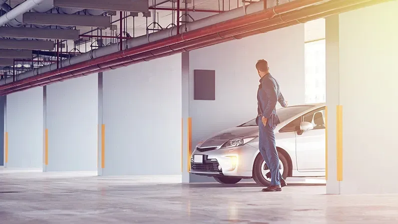 Security system. Full length of a professional confident businessman setting the alarm on his car and standing near his auto in the parking lot