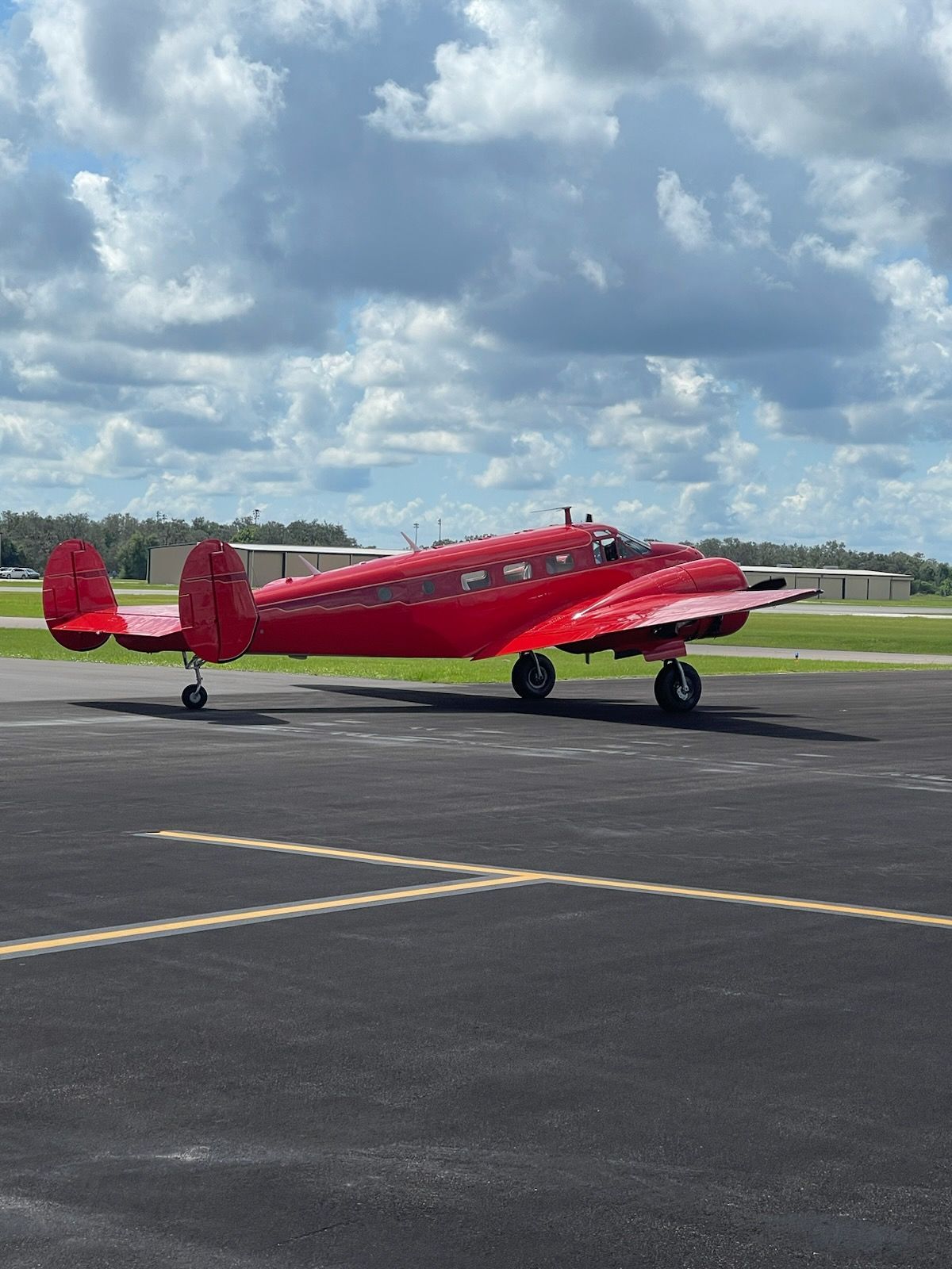 A red airplane is parked on a runway.