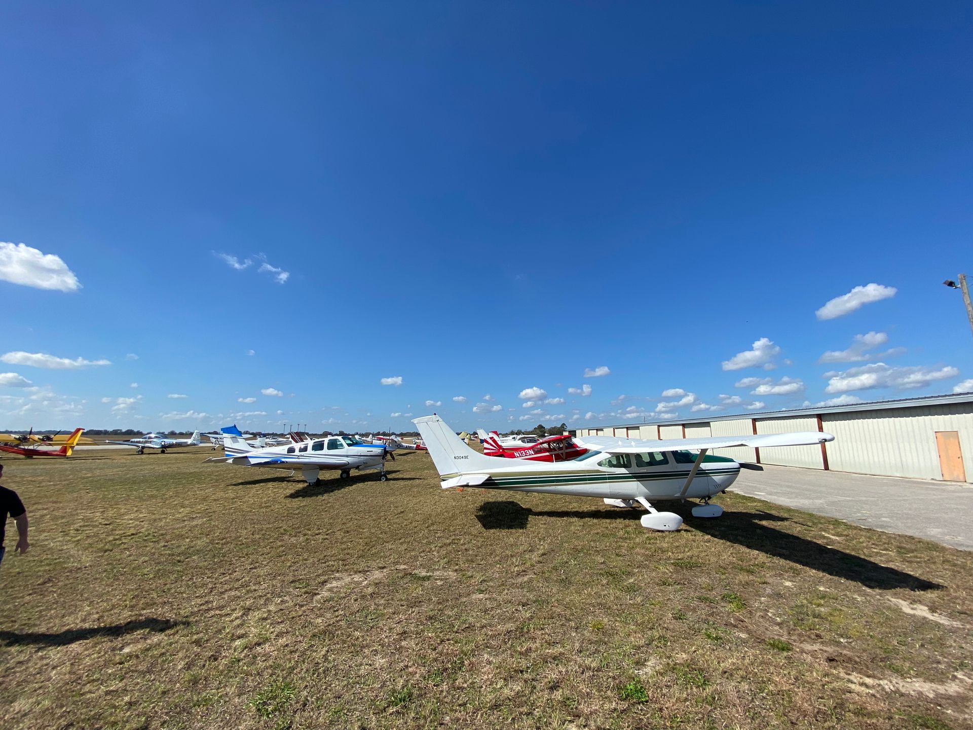 A group of small planes are parked in a grassy field.