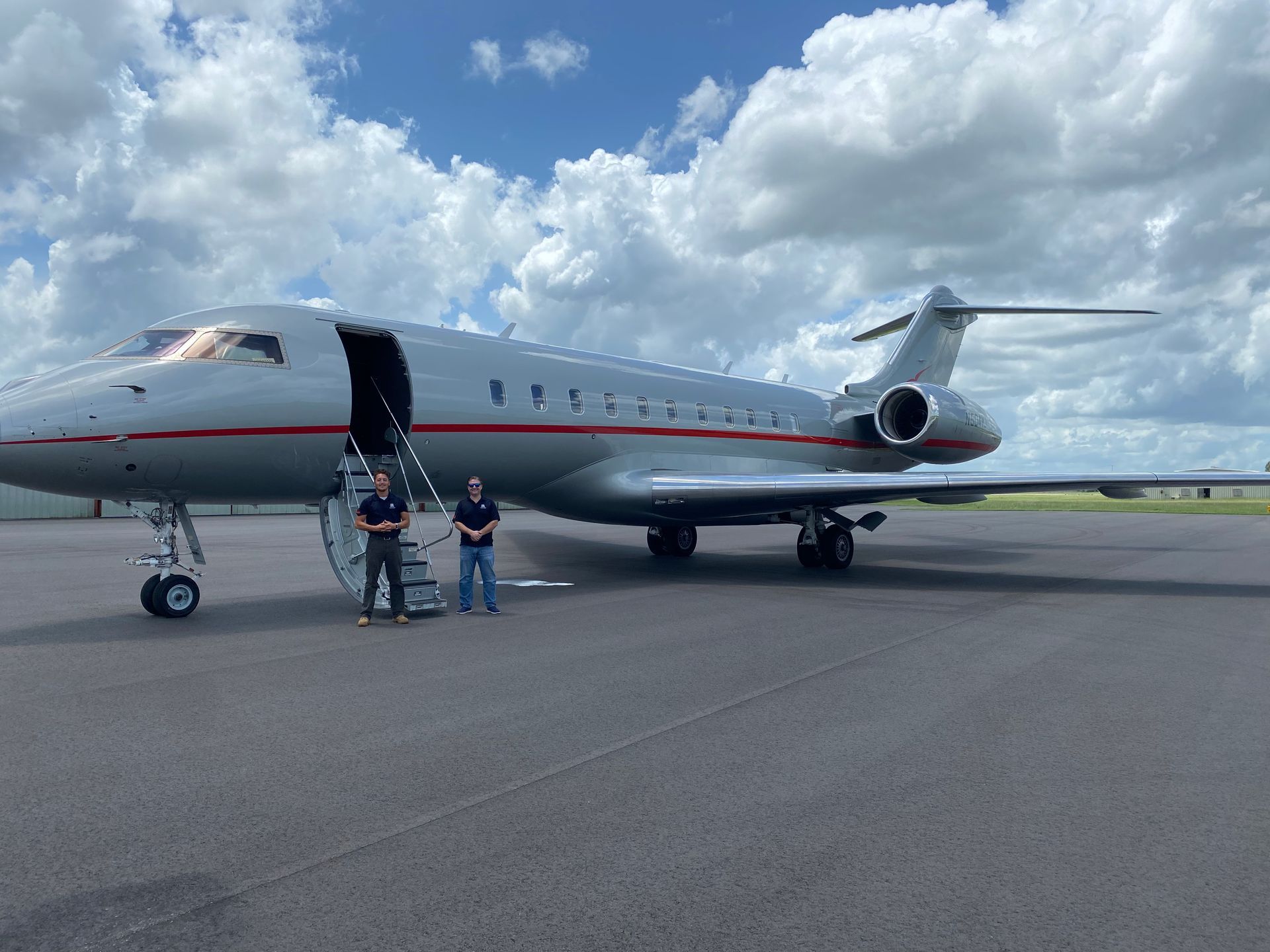 Two men are standing in front of an airplane on a runway.