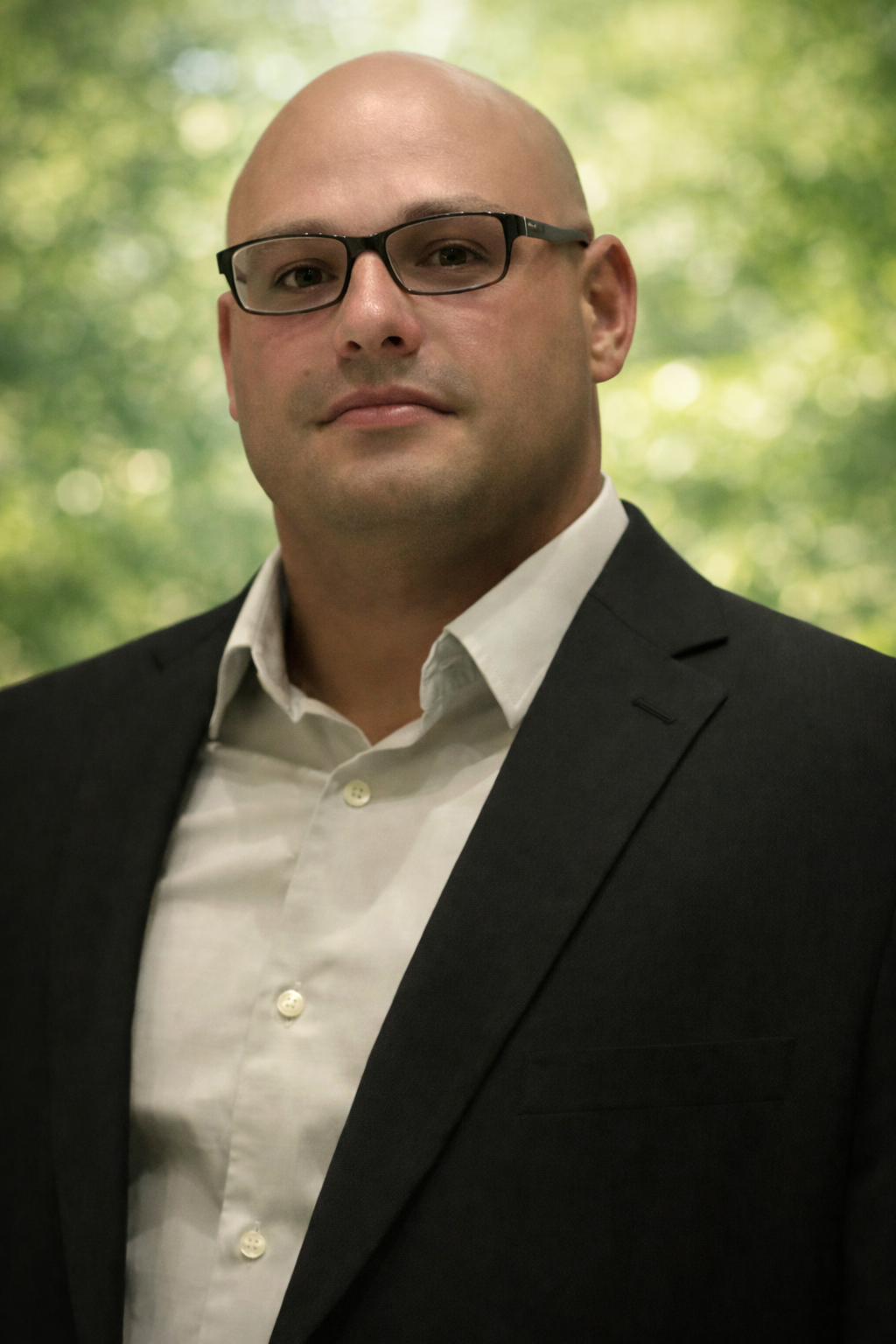 Bald man in glasses and suit jacket, looking at the camera.