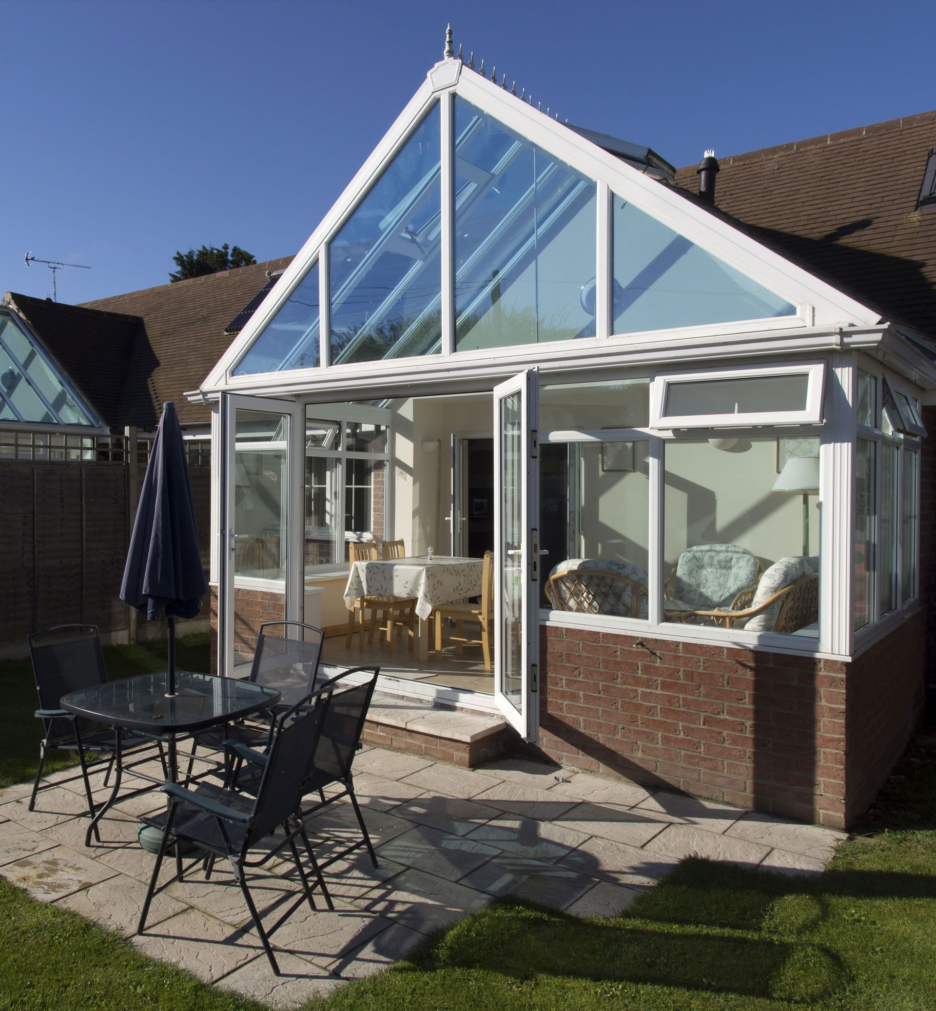 A house with a glass roof and a table and chairs in front of it