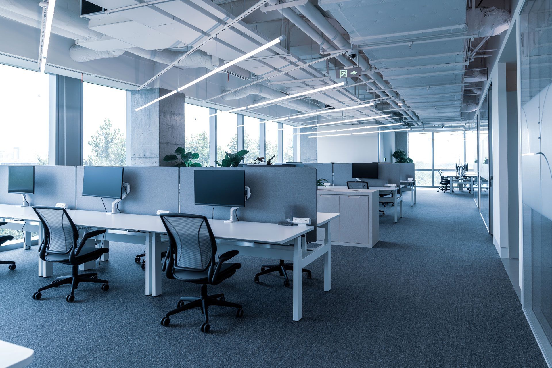 An empty office with a lot of windows and desks and chairs.