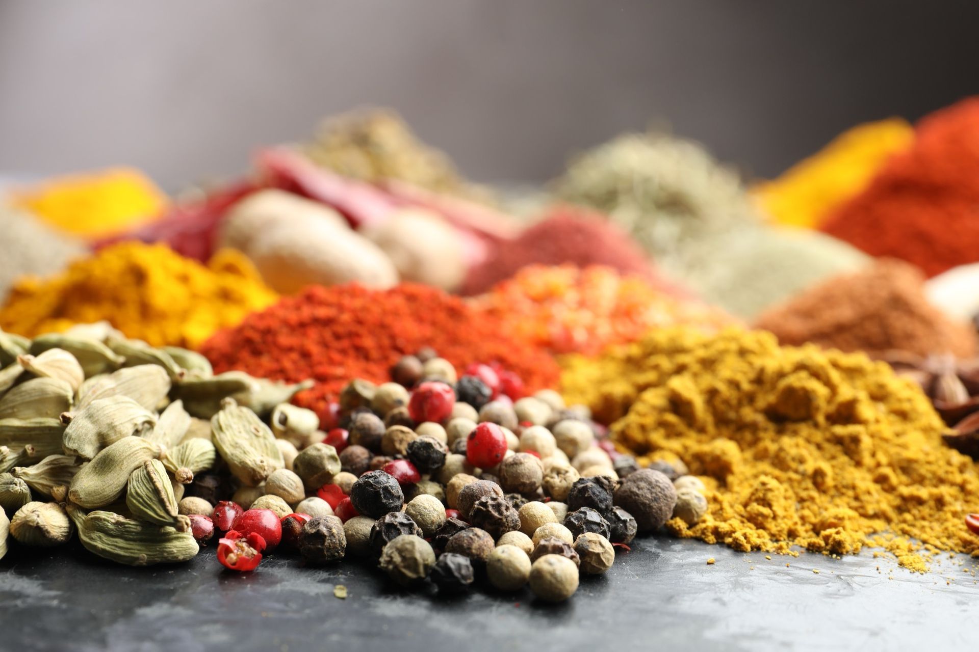 Bowls of spices: paprika, turmeric, and brown spice. Also, cinnamon sticks, peppercorns, cardamom, nutmeg, and bay leaves.