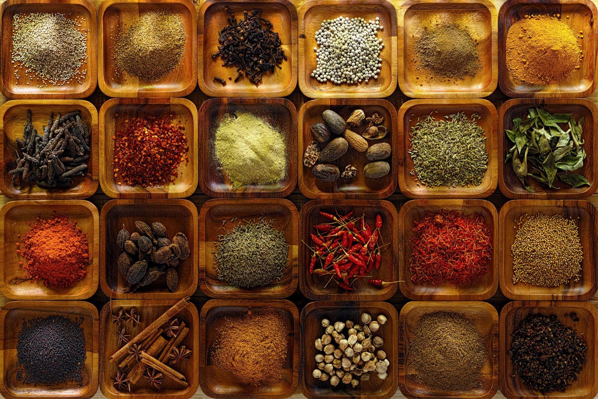 Wooden trays filled with various colorful spices and herbs.