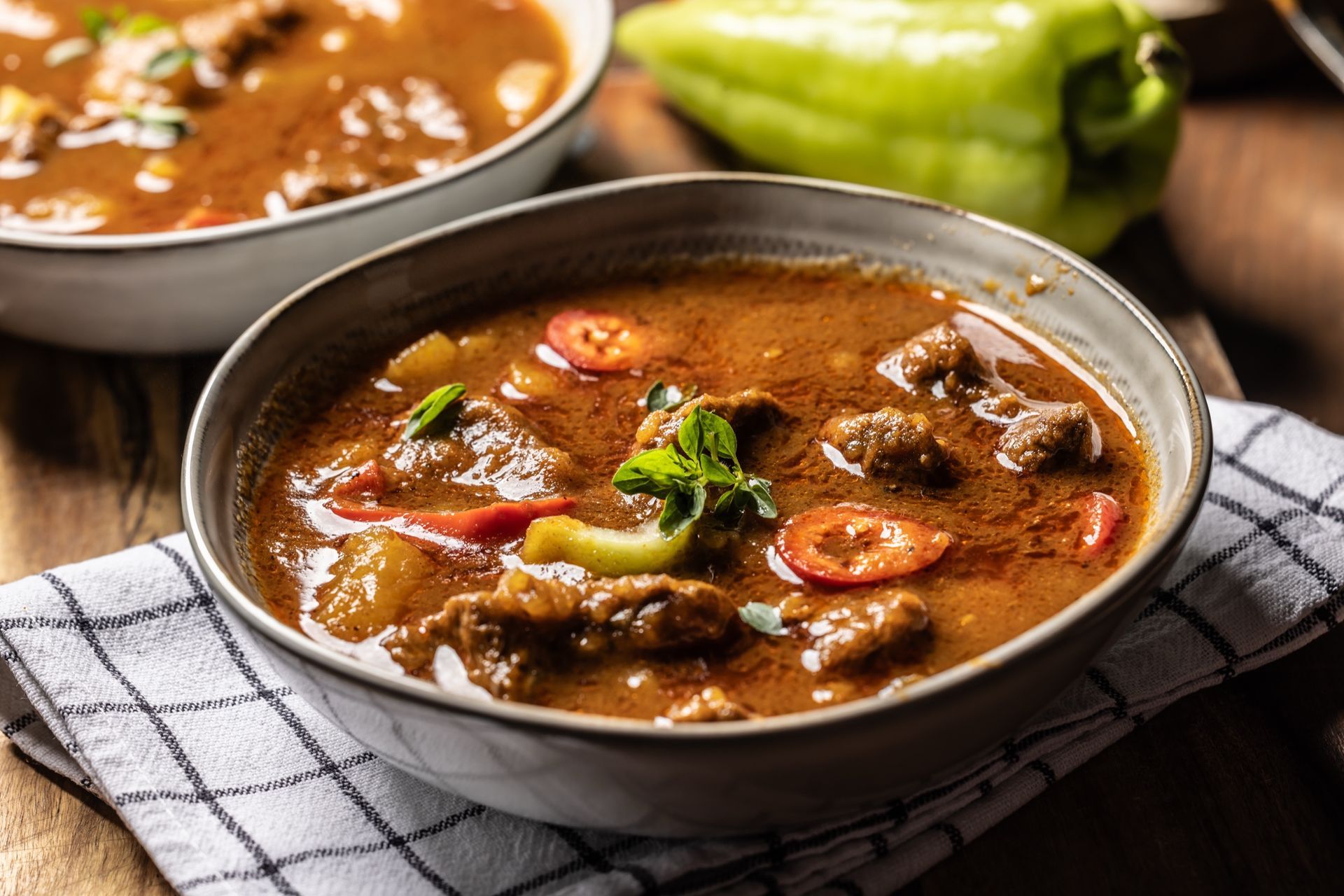 Bowls of stew with meat, vegetables, in a dark brown sauce.