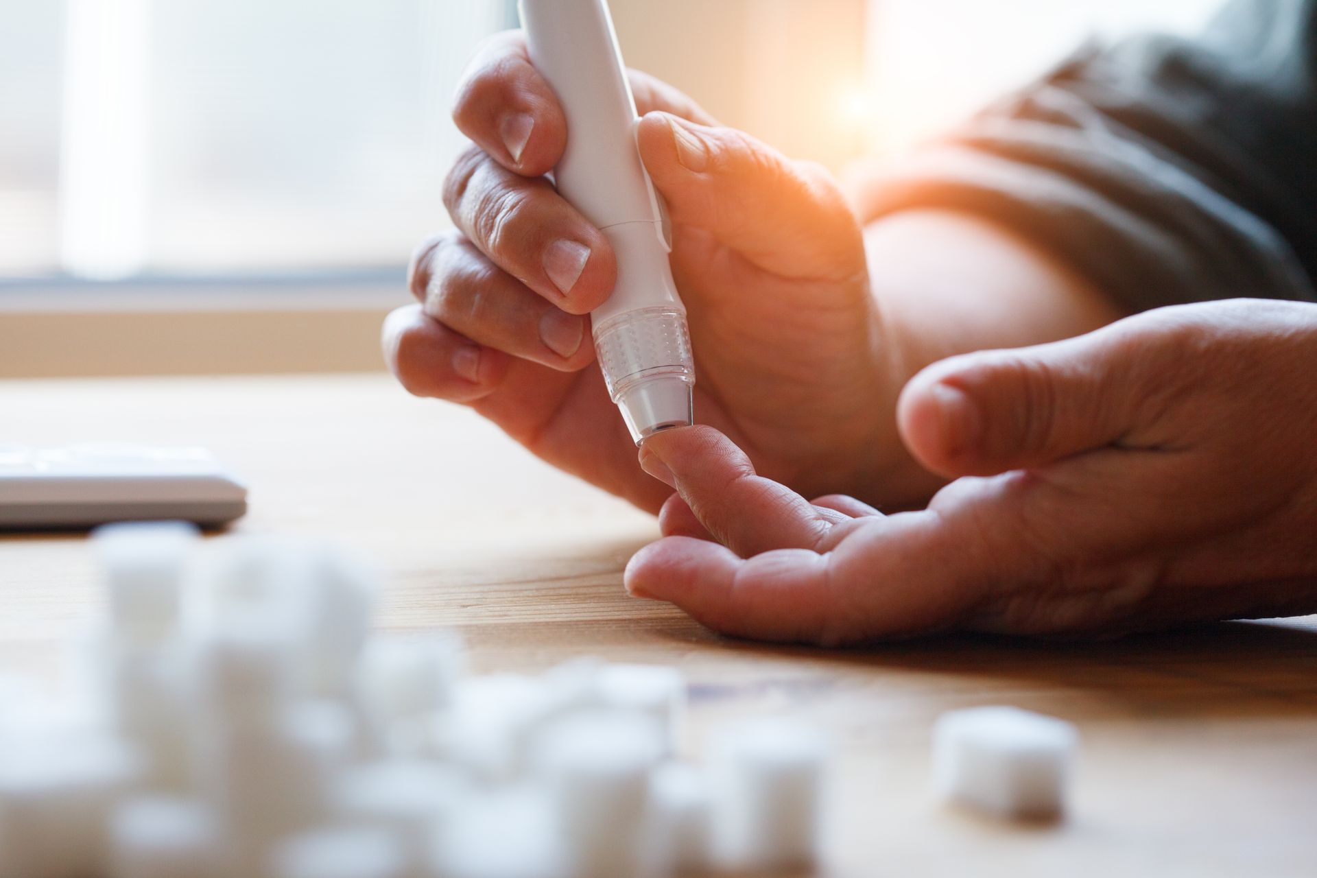 Two hands gently holding a small foot on a table, with a blurred medical setting in the background