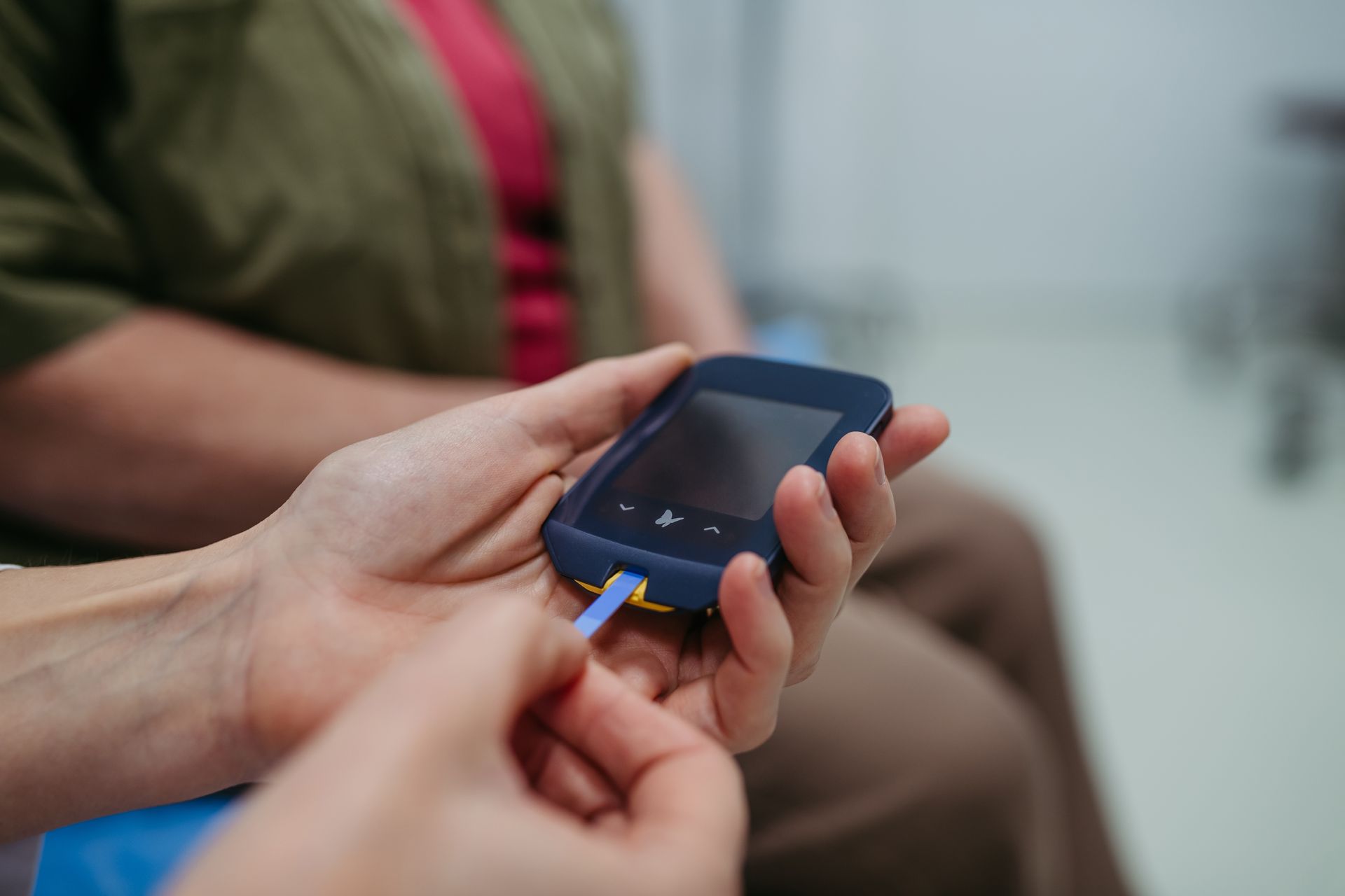 Hands connecting a blue charging cable to a smartphone held in someone’s lap