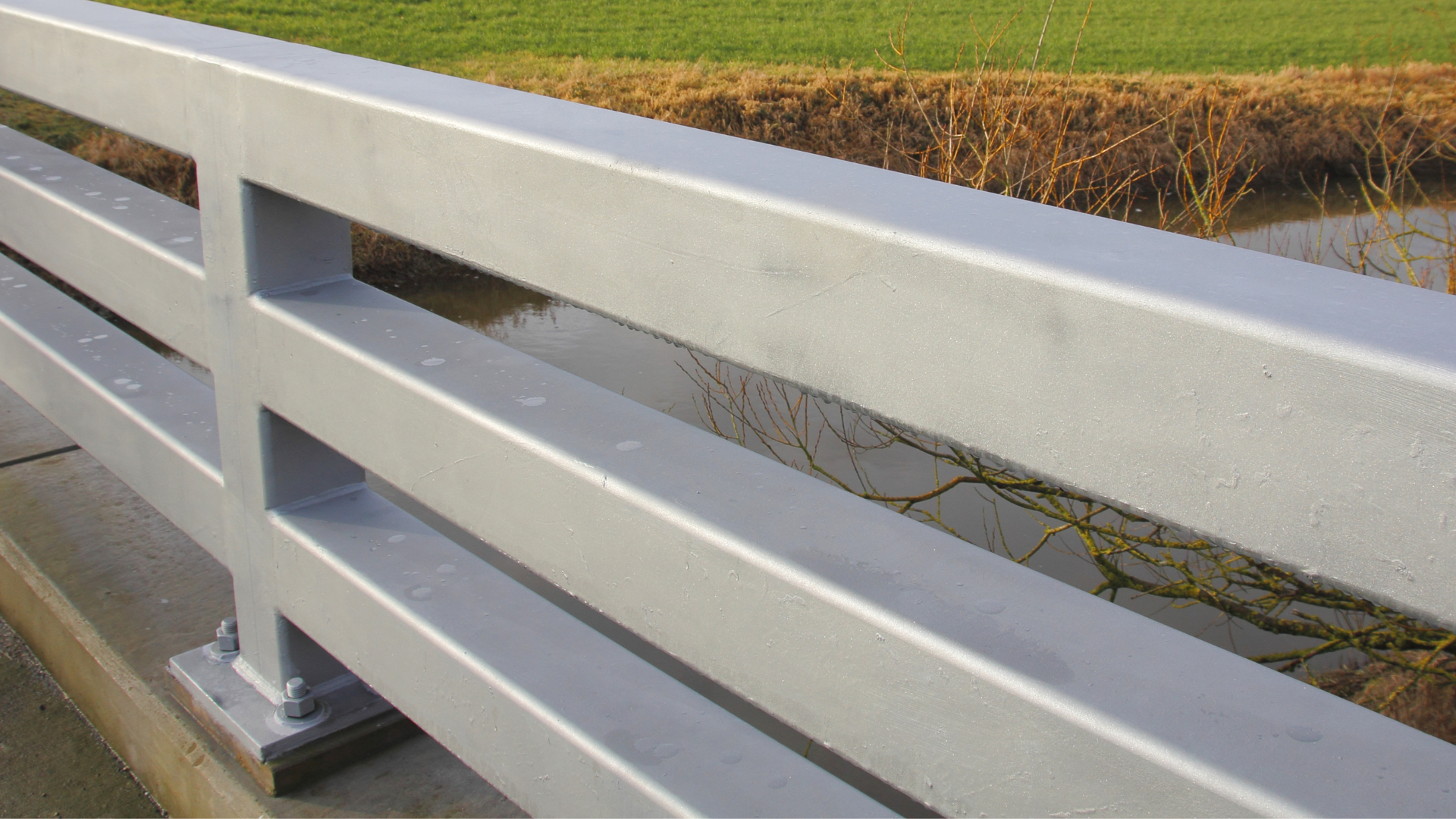 a close up of a bridge railing with a field in the background .