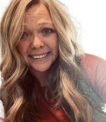 A close-up of amber montague wearing glasses and smiling.
