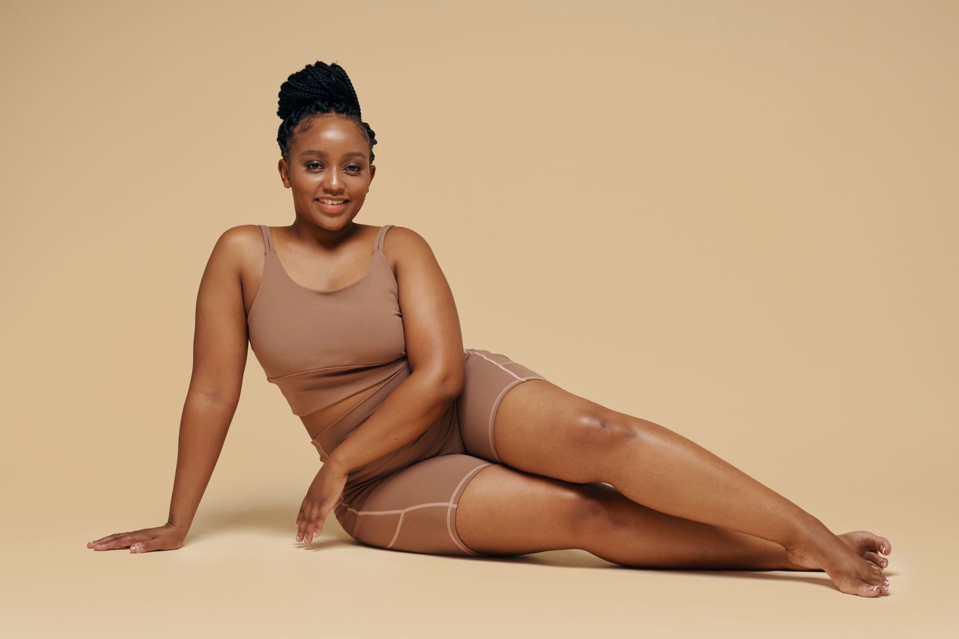 a beautiful woman sitting in a beige bodysuit
