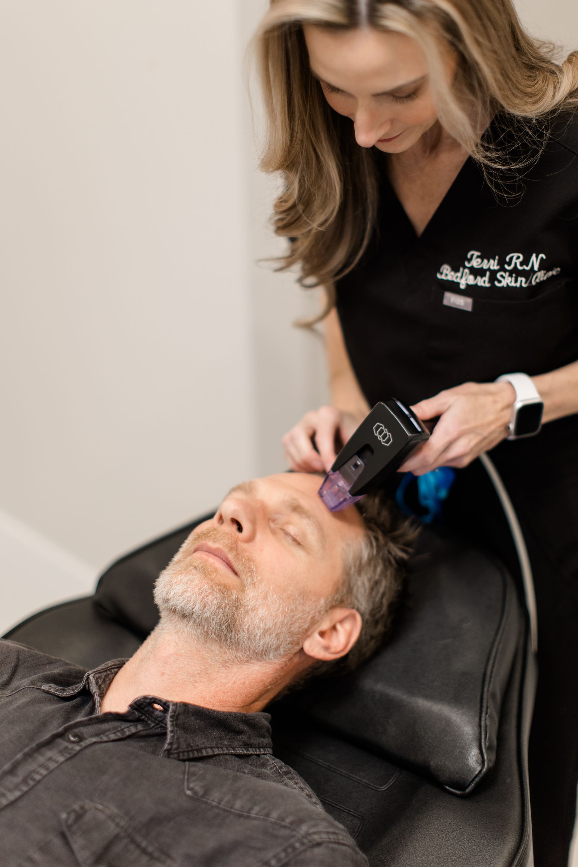 A woman is giving a man a treatment on his face.