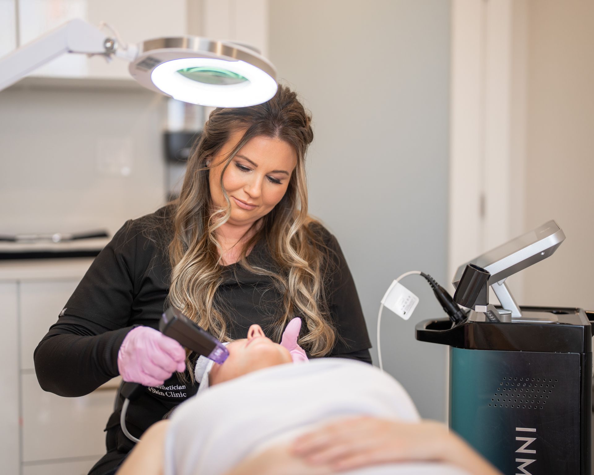 A woman is using a machine on a woman 's face in a beauty salon.