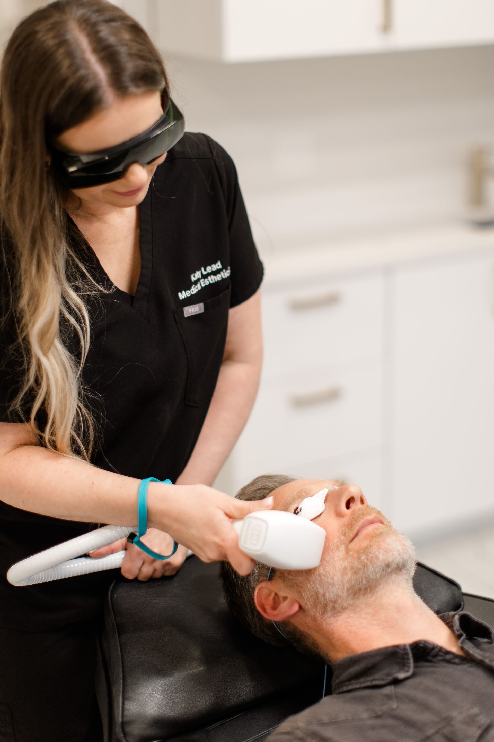 A woman is giving a man a laser treatment on his face.