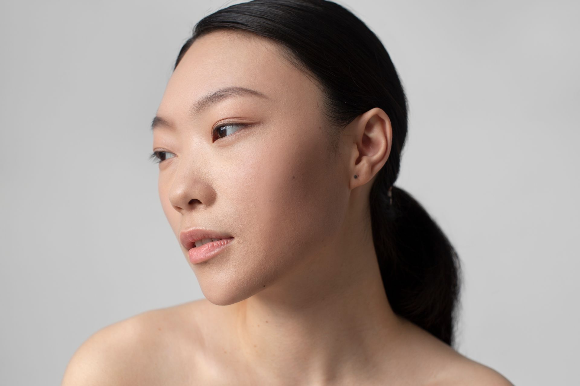 A close up of a woman 's face with a ponytail.