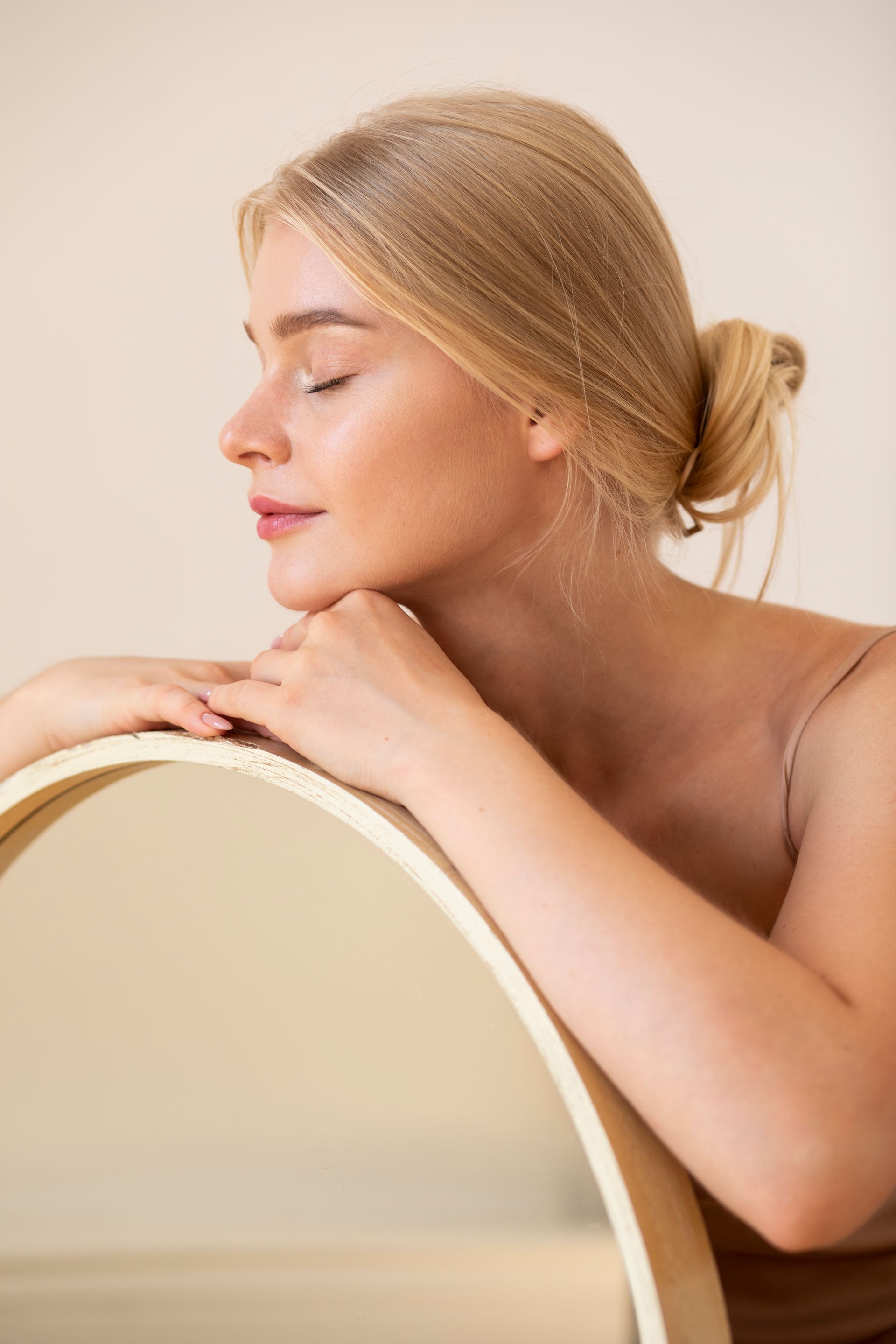 A woman is leaning on a mirror with her eyes closed.