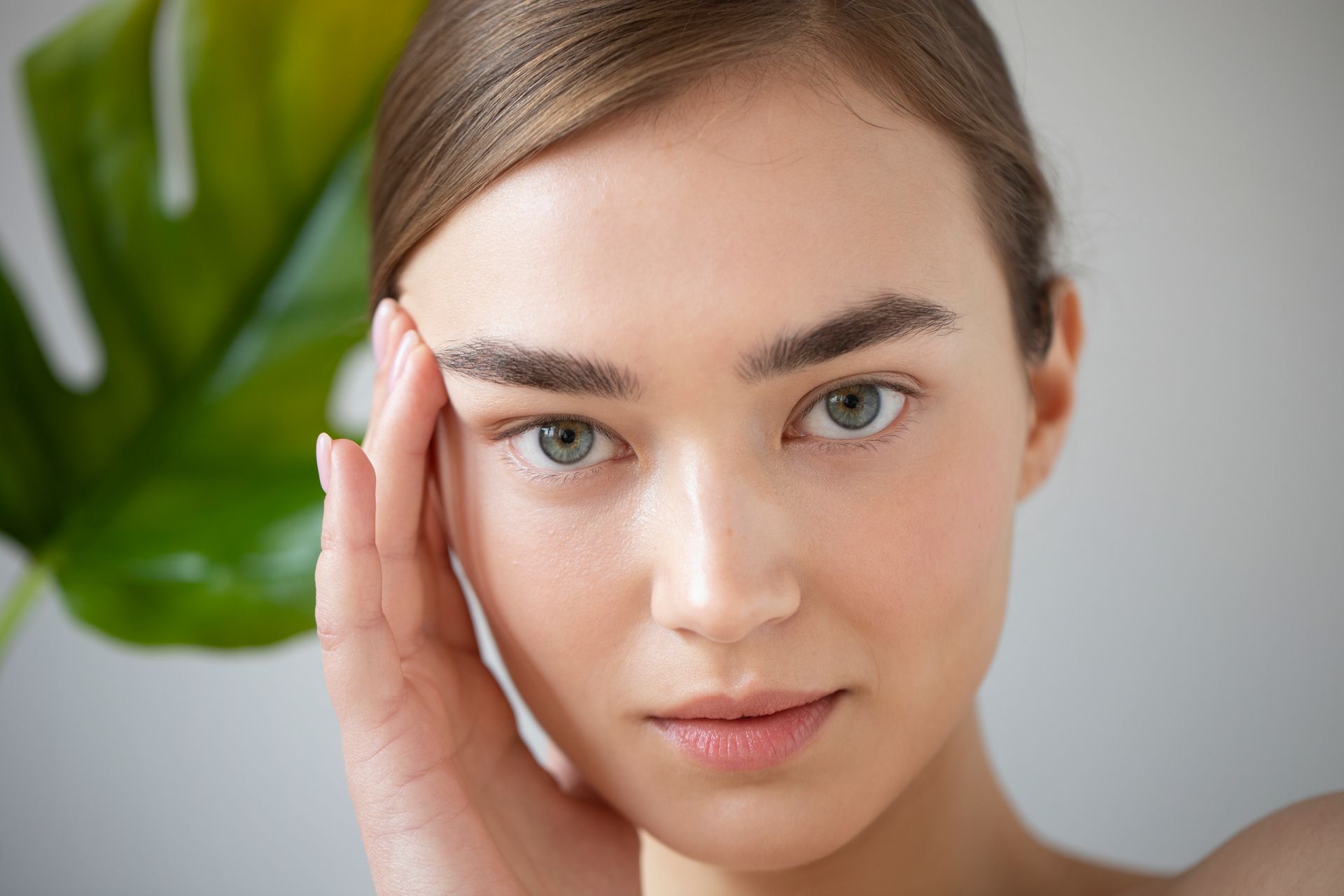 A close up of a woman 's face with a leaf in the background.