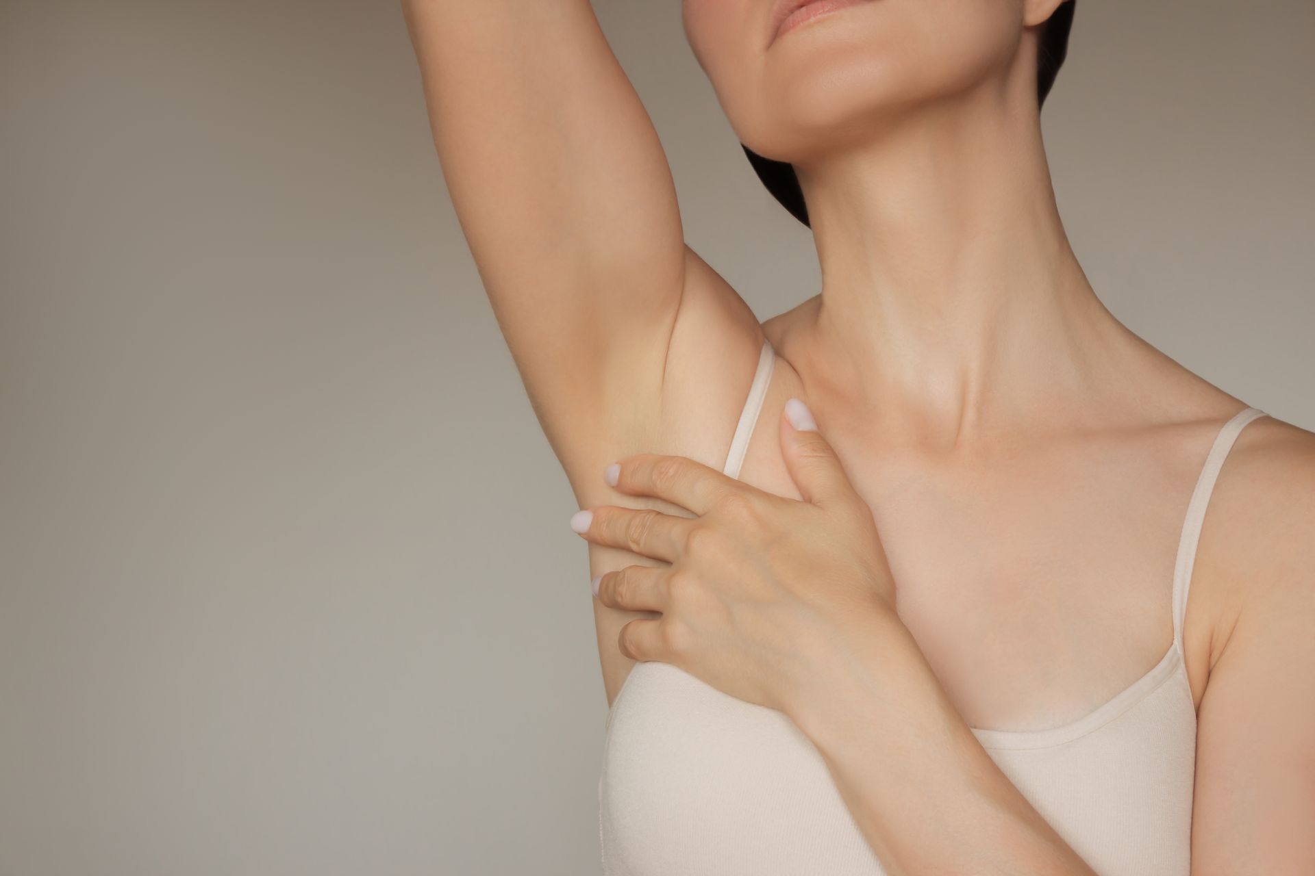 A woman is holding her armpit with her hand.