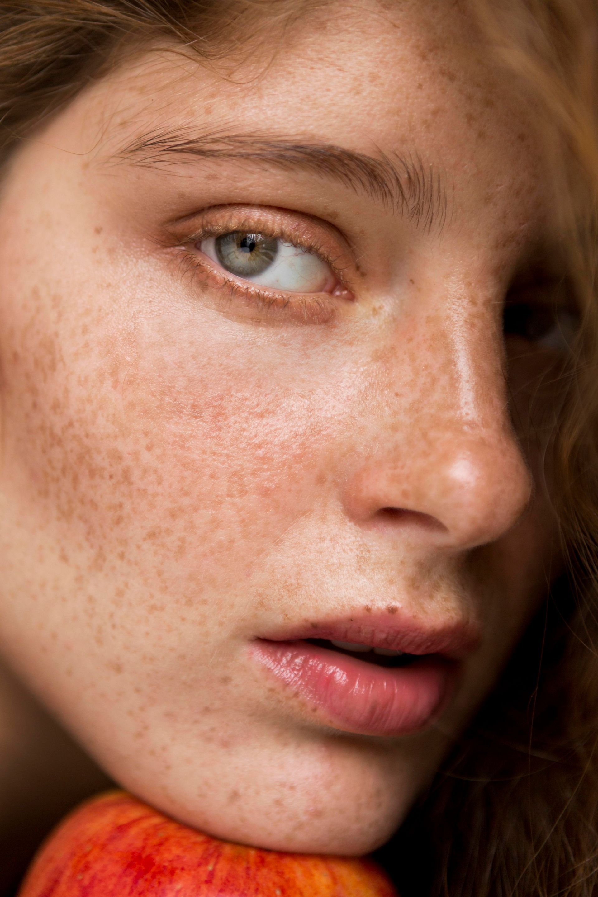 A close up of a woman 's face with an apple on her shoulder.