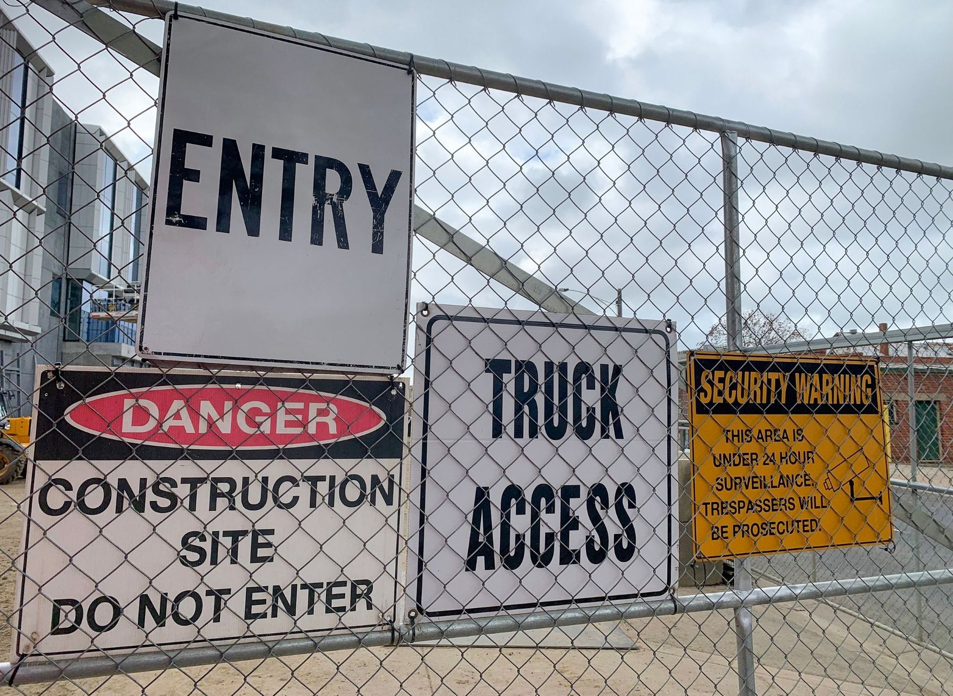 Chain-link fence displaying four signs: 