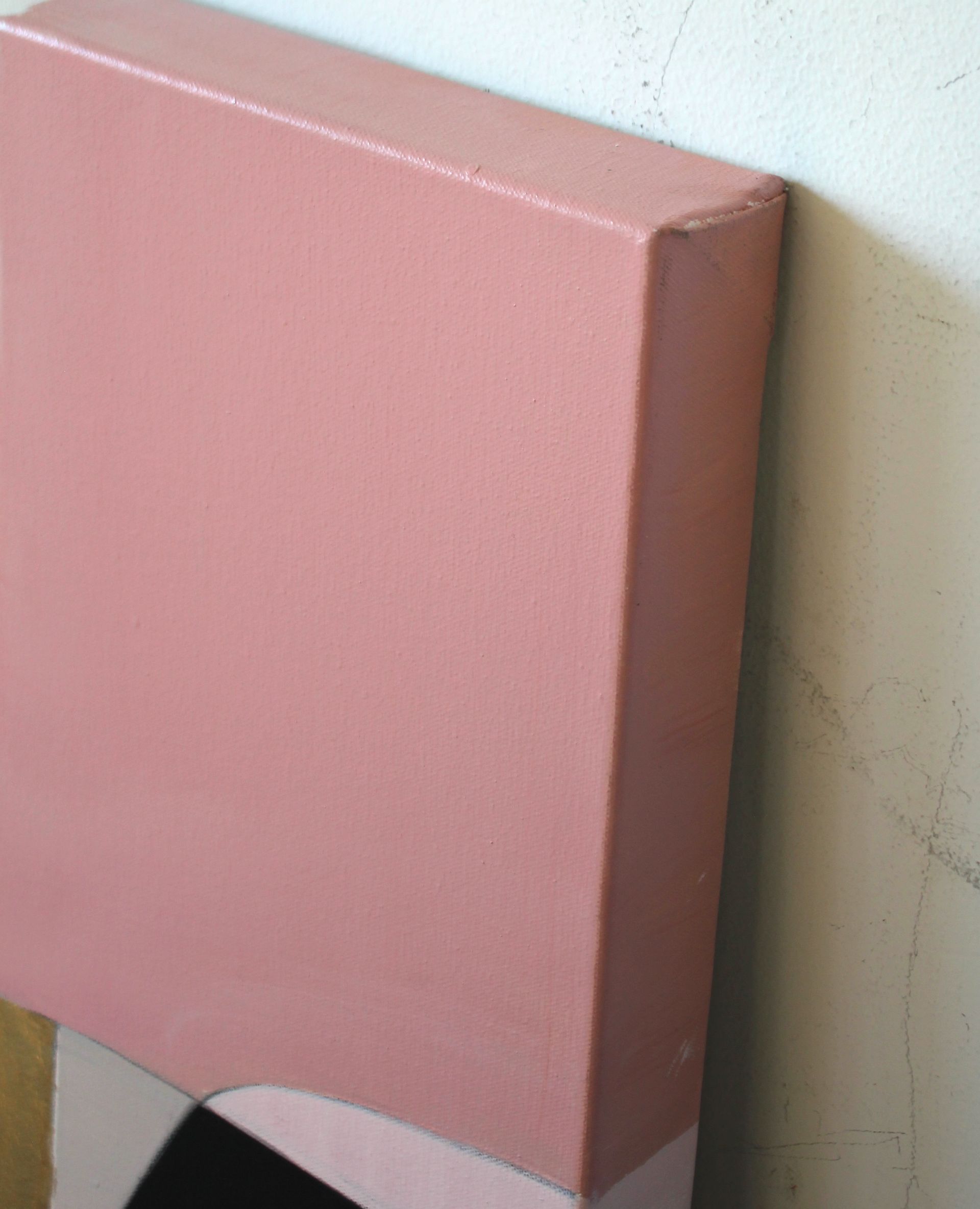 A pink box is leaning against a white wall.