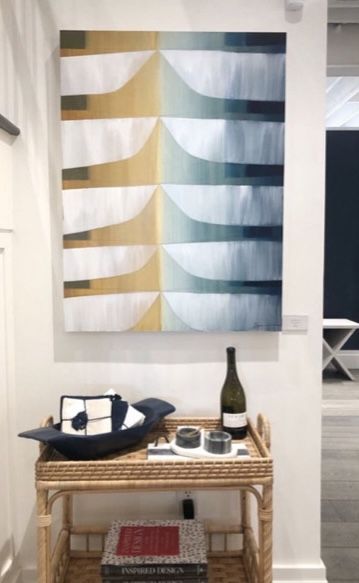 A table with a bottle of wine and a painting on the wall above it