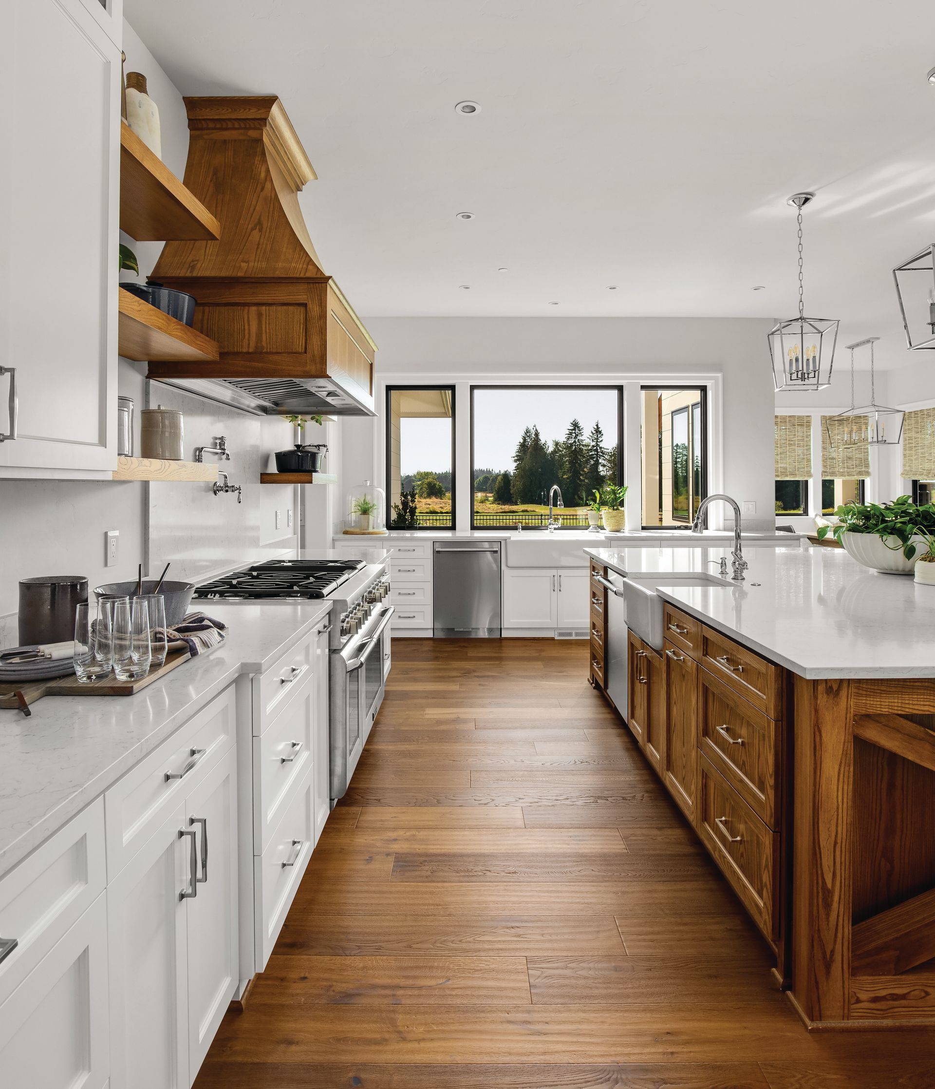 A bright kitchen with white cabinets, a wood-paneled island and vent hood, quartz countertops, and large windows.