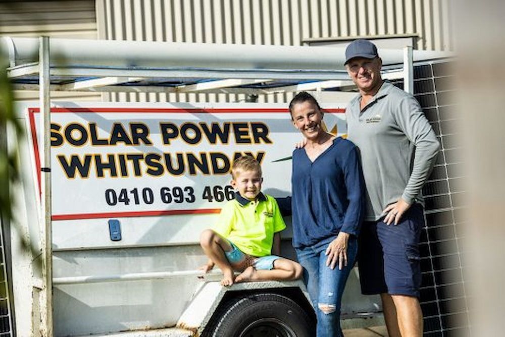 A Family Is Standing In Front Of A Solar Power Trailer — Solar Power Whitsunday In Cannon Valley, QLD