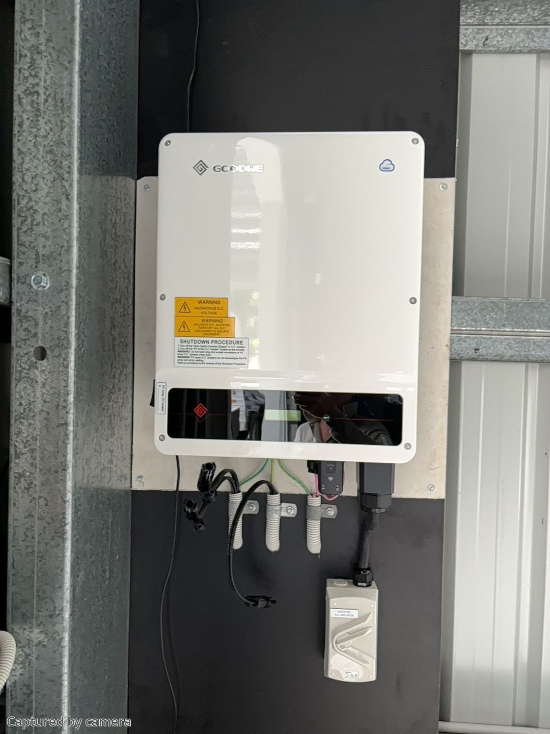 A Man Is Installing A Solar Inverter On A Wall — Solar Power Whitsunday In Cannon Valley, QLD