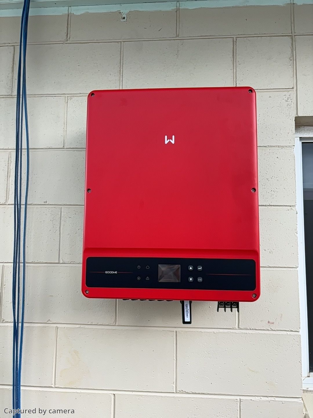 A Man Is Installing A Solar Inverter On A Wall — Solar Power Whitsunday In Bowen, QLD