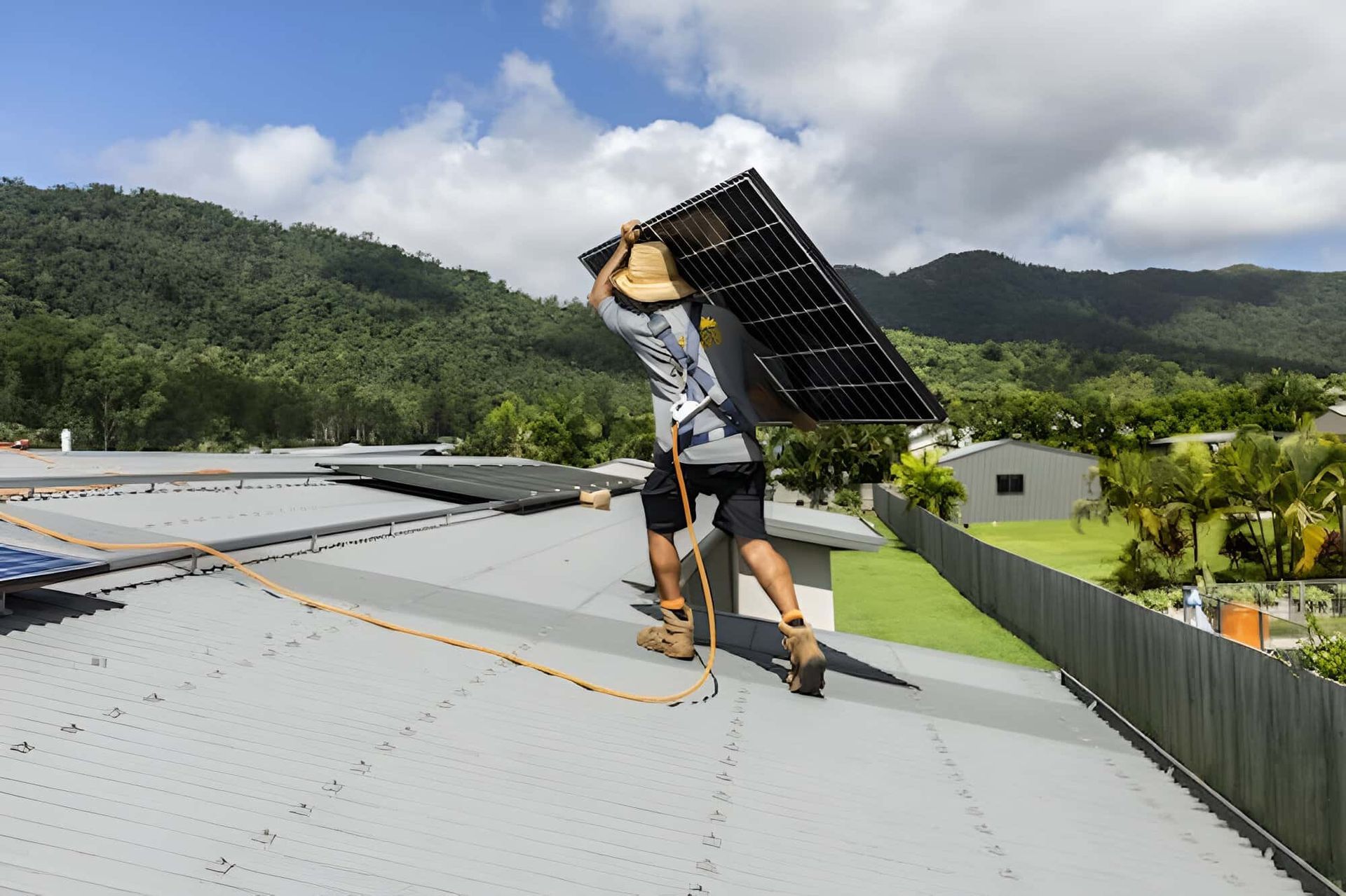 A Man Is Carrying A Solar Panel On His Back On A Roof — Solar Power Whitsunday In Cannon Valley, QLD