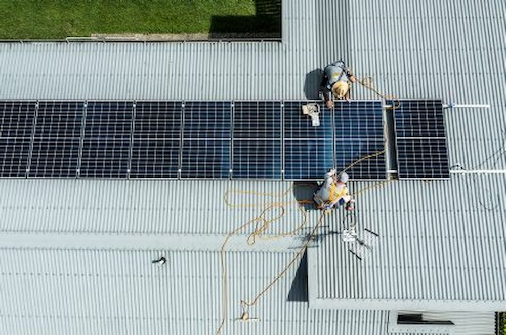 A Group Of People Are Installing Solar Panels On The Roof Of A Building — Solar Power Whitsunday In Cannon Valley, QLD